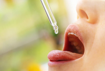 Frau tropft CBD-Öl auf Zunge