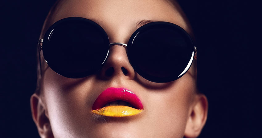 Frau mit Sonnenbrille und pink-gelbem Lippenstift