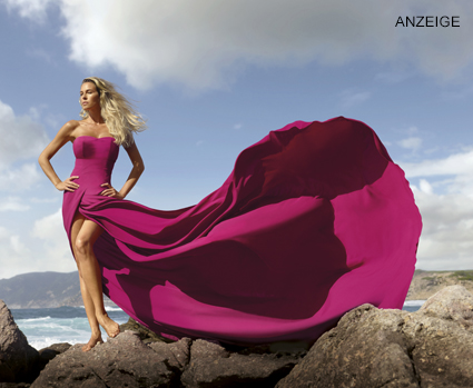 Frau mit schöner Haut auf einem Felsen, die ein pinkes Kleid trägt