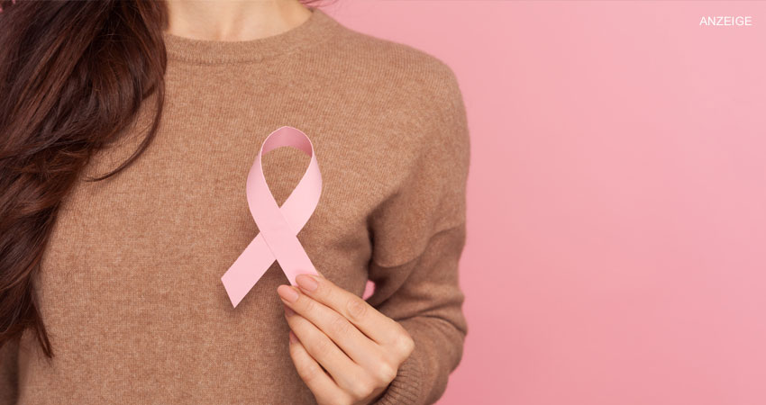 Frau, die sich rosa Brustkrebs-Schleife vor ihren Oberkörper hält