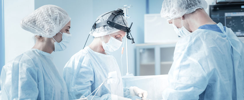 Fachärzte und OP-Personal stehen um den Operationstisch herum, operieren, arbeiten zusammen 