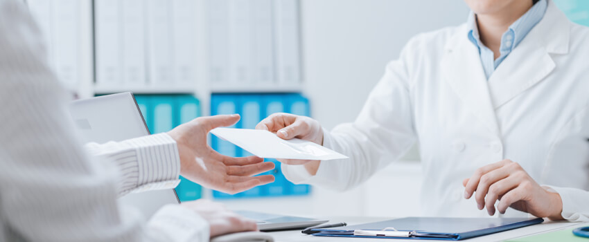 Ärztin übergibt einen Umschlag an die Patientin